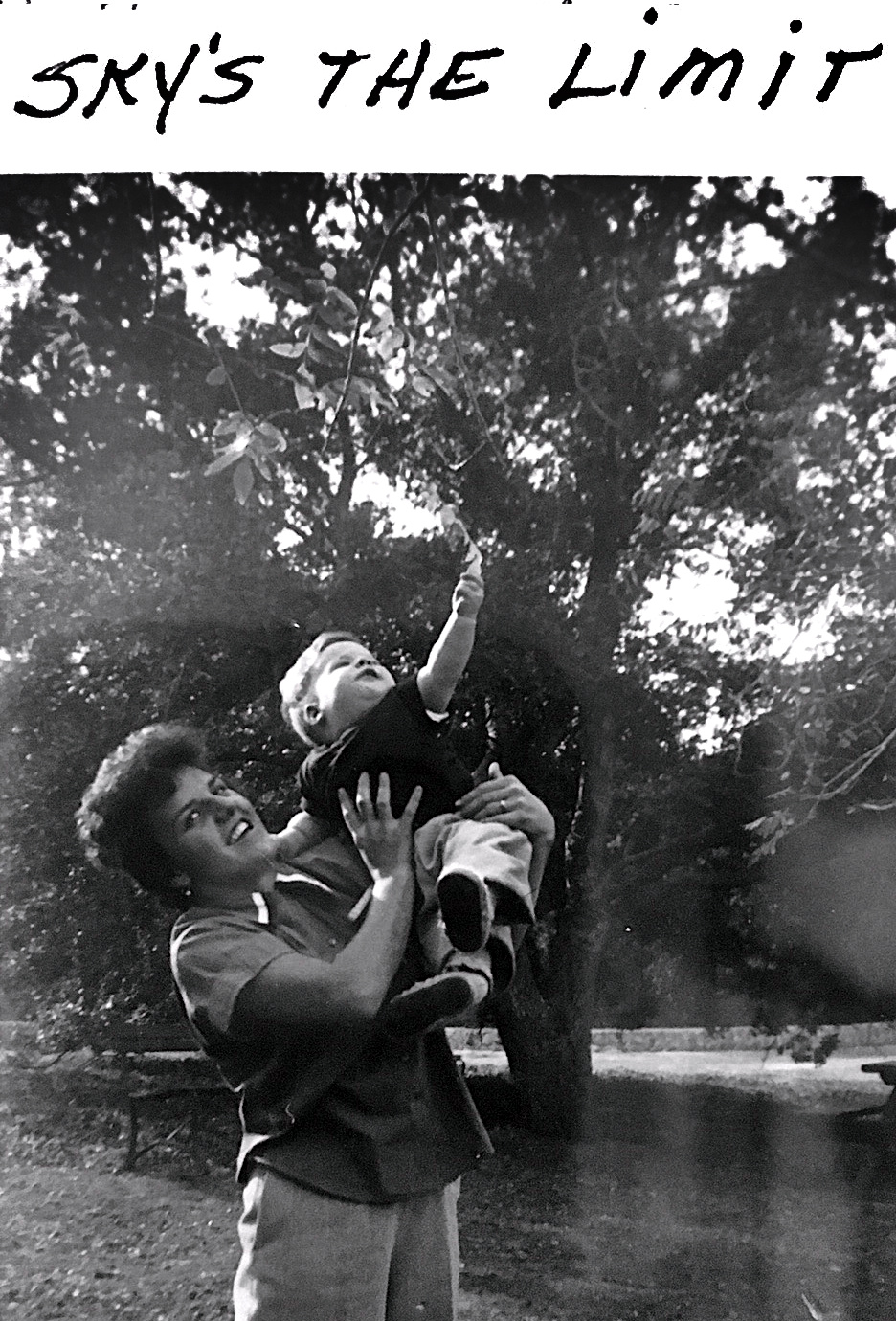 Woman holding up small boy as he reaches for a tree. Text above says "Sky's the limit."
